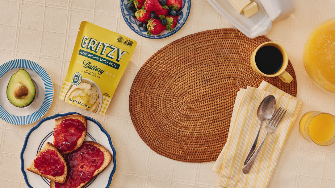 Breakfast table featuring Gritzy Buttery Ready Grits with toast, fruit, coffee, and orange juice